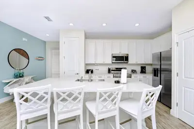 a kitchen with white cabinets and a white table and chairs at Flip Flops & Fairytales Waterfront With Margaritaville Resort & Island H2O & Island H2O Access - 3021Cs in Orlando