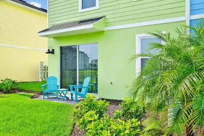 a house with two blue chairs on a patio at Key Lime Villa Near Disney With Margaritaville Resort & Island H20 Waterpark Access - 3073Cs in Orlando