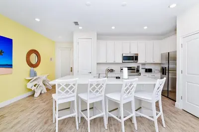 a kitchen with white chairs and a large white table at Lovely Villa Near Disney With Margaritaville Resort & Island H20 Access - 8146Cp in Orlando