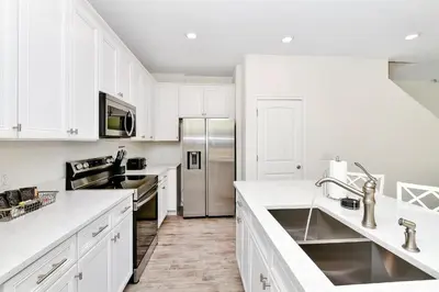 a kitchen with white cabinets and a stainless steel refrigerator at Lovely Villa Near Disney With Margaritaville Resort & Island H20 Access - 8146Cp in Orlando