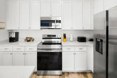 a kitchen with white cabinets and a black stove top oven at Lovely Villa Near Disney With Margaritaville Resort & Island H20 Access - 8201Su in Orlando