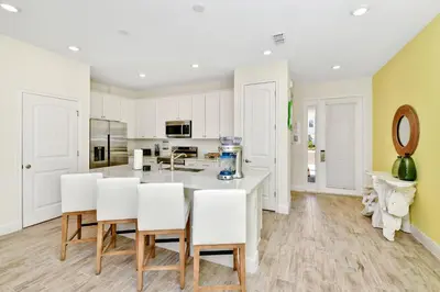 a kitchen with white cabinets and a table and chairs at Colorful Villa Near Disney With Margaritaville Resort & Island H20 Waterpark Access - 3140Cs in Orlando