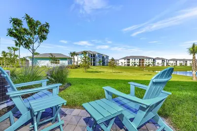 a pair of blue chairs on a patio with a yard at Pink Bliss Villa Near Disney With Margaritaville Resort & Island H20 Access - 3205Cs in Orlando