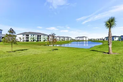 a park with a palm tree and a lake at Pink Bliss Villa Near Disney With Margaritaville Resort & Island H20 Access - 3205Cs in Orlando