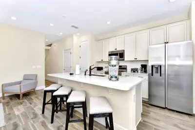 a kitchen with white cabinets and a counter with stools at Pink Bliss Villa Near Disney With Margaritaville Resort & Island H20 Access - 3205Cs in Orlando