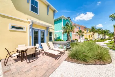 a patio with chairs and a table in front of a house at Sunkissed Cottage With Hot Tub Near Disney With Margaritaville Resort & Island H2O Access - 8046Su in Orlando