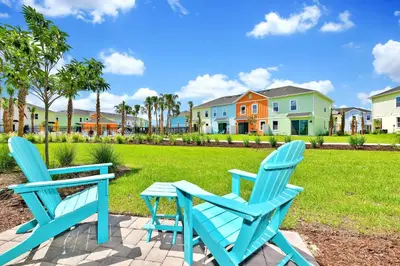 two blue chairs and a table on a patio with houses at Sand Delight Near Disney With Margaritaville Resort & Island H20 Waterpark Access - 3152Cs in Orlando