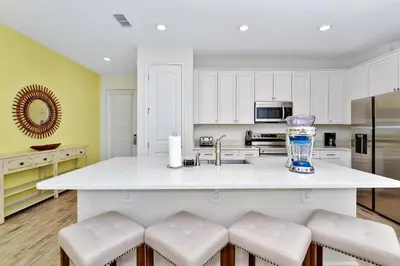 a kitchen with a large white island with stools at Sand Delight Near Disney With Margaritaville Resort & Island H20 Waterpark Access - 3152Cs in Orlando