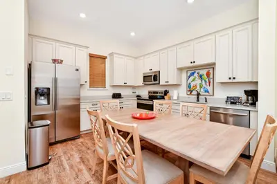 a kitchen with a wooden table and a refrigerator at Pina Cabana Cottage Near Disney With Margaritaville Resort & Island H2O Access - 3070Kl in Orlando