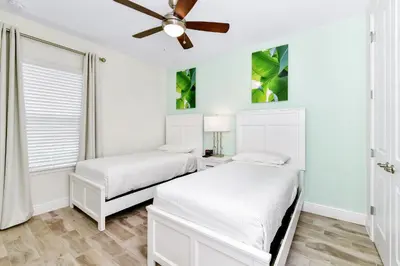 two beds in a white room with a ceiling fan at Lime Green Villa Near Disney With Margaritaville Resort & Island H20 Waterpark Access - 2930Cl in Orlando