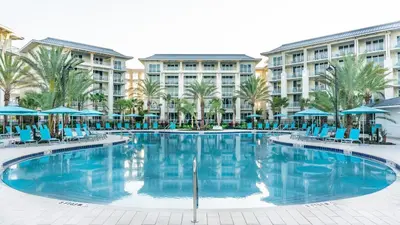 a large swimming pool with blue chairs and umbrellas at Sunshine Cottage With Private Pool Near Disney With Margaritaville Resort & Island H20 Access - 8165Su in Orlando