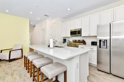 a kitchen with white cabinets and a kitchen island with stools at Lovely Villa Near Disney With Margaritaville Resort & Island H20 Waterpark Access - 2947Cl in Orlando