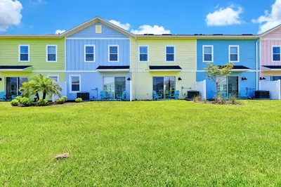a large apartment building with a green yard at Palm Tree Paradise Villa Near Disney With Margaritaville Resort & Island H20 Waterpark Access - 3113Cs in Orlando