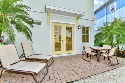 a patio with chairs and a table in front of a house at The Pearl Cottage Near Disney With Margaritaville Resort & Island H20 Waterpark Access - 3078Pi in Orlando