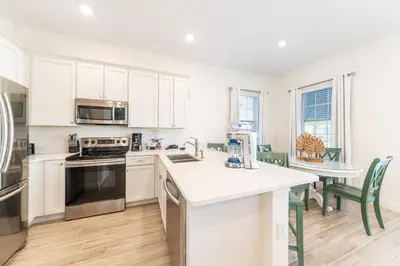 a kitchen with white cabinets and a table with chairs at Peachside Cottage Near Disney With Margaritaville Resort & Island H2O Access - 8037Dr in Orlando
