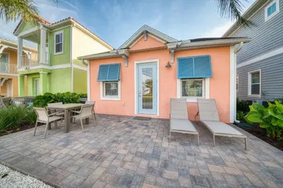 a patio with a table and chairs in front of a house at Peachside Cottage Near Disney With Margaritaville Resort & Island H2O Access - 8037Dr in Orlando