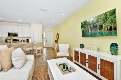 a living room with a white couch and a kitchen at Serene Villa Near Disney With Margaritaville Resort Island H20 Access - 8167Cp in Orlando