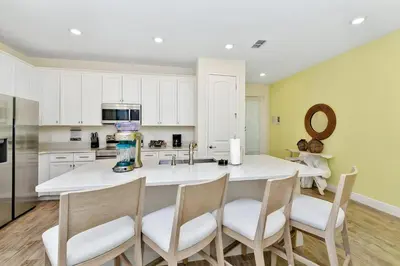 a kitchen with a large white island with four chairs at Serene Villa Near Disney With Margaritaville Resort Island H20 Access - 8167Cp in Orlando