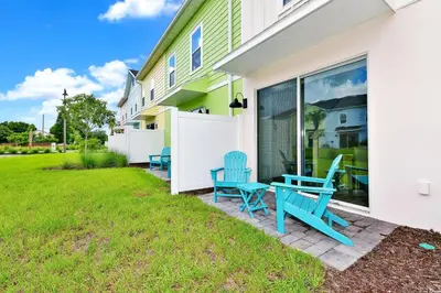 a patio with blue chairs next to a house at Sun Filled Villa Near Disney With Margaritaville Resort & Island H20 Access - 8119Cp in Orlando