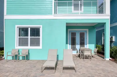 a blue building with chairs and a table in front of it at Ocean Blue Cove Cottage Near Disney With Margaritaville Resort & Island H2O Access - 8020Ls in Orlando