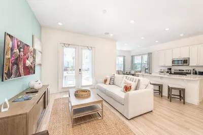 a living room with a white couch and a kitchen at Ocean Blue Cove Cottage Near Disney With Margaritaville Resort & Island H2O Access - 8020Ls in Orlando
