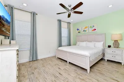 a bedroom with a white bed and a ceiling fan at Colorful Villa Near Disney With Margaritaville Resort & Island H20 Waterpark Access- 2919Cl in Orlando