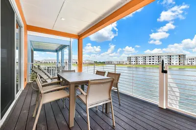 a table and chairs on a balcony with a view of the water at Waters Edge Cottage Near Disney With Margaritaville Resort & Island H20 Access - 8129Su in Orlando