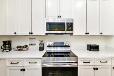a kitchen with white cabinets and a stove and a microwave at Colorful Villa Near Disney With Margaritaville Resort & Island H20 Access - 8195Cp in Kissimmee