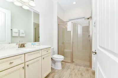 a white bathroom with a toilet and a shower at Sandy Toes Cottage With Private Pool Near Disney And Margaritaville Resort & Island H2O Access - 8032St in Orlando