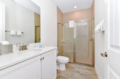 a white bathroom with a toilet and a shower at Pink Villa Near Disney With Margaritaville Resort & Island H20 Access - 8163Cp in Orlando