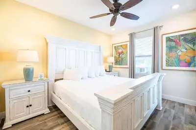 a bedroom with a white bed and a ceiling fan at Sunkissed Cottage With Private Pool Near Disney With Margaritaville Resort & Island H2O Access - 8024Kd in Orlando