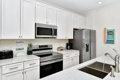 a kitchen with white cabinets and a stainless steel refrigerator at Bright Villa Near Disney With Margaritaville Resort & Island H20 Access - 8191Cp in Orlando