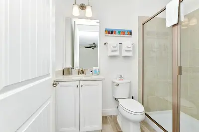 a white bathroom with a toilet and a sink at The Tipsy Turtle Cottage With Private Pool Near Disney With Margaritaville Resort & Island H2O Access - 8012St in Orlando
