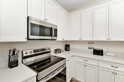 a kitchen with white cabinets and a stove top oven at Lime Green Villa Near Disney With Margaritaville Resort & Island H20 Waterpark Access - 2958Cl in Orlando