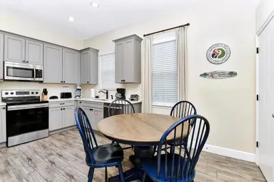 a kitchen with a wooden table and chairs at Lively Cottage With Hot Tub Near Disney With Margaritaville Resort & Island H2O Access - 8030Su in Orlando