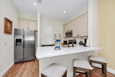 a kitchen with a stainless steel refrigerator and stools at Orange Creamsickle Cottage Near Disney With Margaritaville Resort & Island H20 Waterpark Access - 2980Sr in Orlando