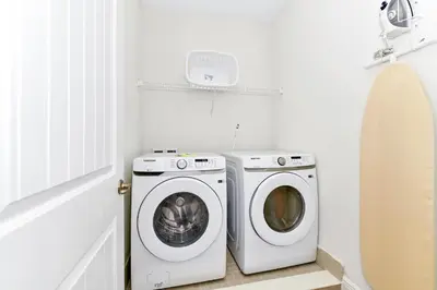 a white laundry room with a washer and dryer at Glimmering Blue Villa Near Disney With Margaritaville Resort & Island H20 Waterpark Access - 3016Cs in Orlando