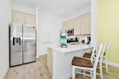a kitchen with a refrigerator and a counter with chairs at Blue Haven Cottage Near Disney With Margaritaville Resort & Island H20 Waterpark Access - 7996Ls in Orlando