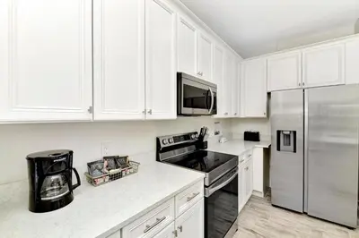 a kitchen with white cabinets and a stainless steel refrigerator at Sun Filled Villa Near Disney With Margaritaville Resort & Island H20 Access - 8183Cp in Kissimmee
