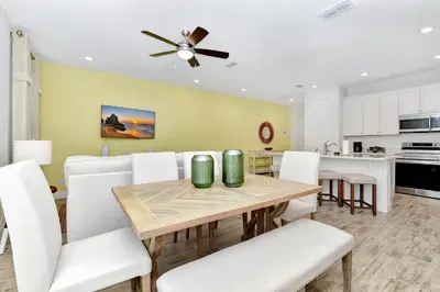 a kitchen and dining room with a table and white chairs at Sun Filled Villa Near Disney With Margaritaville Resort & Island H20 Access - 8183Cp in Kissimmee