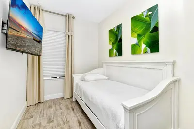 a bedroom with a white bed and paintings on the wall at Sun Filled Villa Near Disney With Margaritaville Resort & Island H20 Access - 8183Cp in Kissimmee