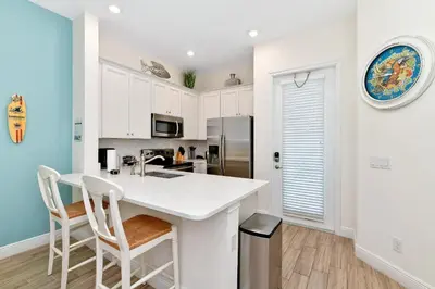 a kitchen with white cabinets and a white counter top at Breezy Green Cottage With Private Hot Tub Near Disney With Margaritaville Resort & Island H2O Access - 3055Pi in Orlando
