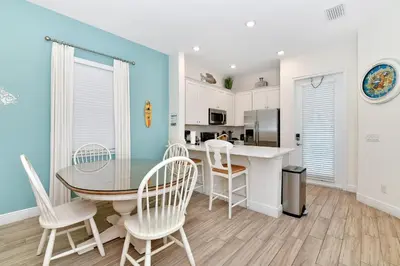 a kitchen and dining room with a table and chairs at Breezy Green Cottage With Private Hot Tub Near Disney With Margaritaville Resort & Island H2O Access - 3055Pi in Orlando