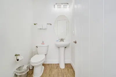 a white bathroom with a toilet and a sink at Tequila Sunrise Cottage With Private Hot Tub Near Disney With Margaritaville Resort & Island H2O Access - 8008Dr in Orlando