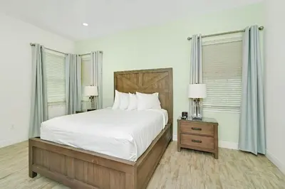 a bedroom with a large bed and two windows at Tequila Sunrise Cottage With Private Hot Tub Near Disney With Margaritaville Resort & Island H2O Access - 8008Dr in Orlando