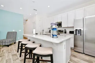 a kitchen with a counter with stools and a refrigerator at Relaxed Villa Near Disney With Margaritaville Resort & Island H20 Waterpark Access - 3169Cs in Orlando