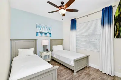 two beds in a bedroom with a ceiling fan at Cozy Villa Near Disney With Margaritaville Resort & Island H20 Waterpark Access - 2976Or in Orlando
