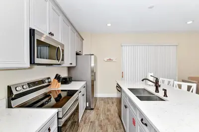 a kitchen with white cabinets and a stainless steel refrigerator at Tropical Villa Near Disney With Margaritaville Resort & Island H20 Waterpark Access - 3005Cs in Orlando
