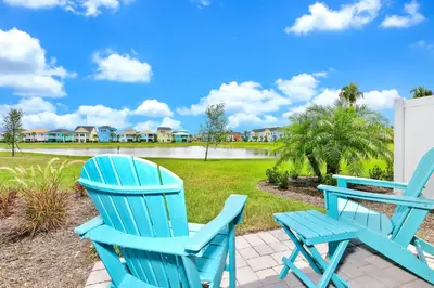 two blue chairs sitting on a patio in front of a yard at Tropical Villa Near Disney With Margaritaville Resort & Island H20 Waterpark Access - 3005Cs in Orlando