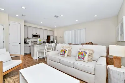 a living room with a white couch and a kitchen at Tropical Villa Near Disney With Margaritaville Resort & Island H20 Waterpark Access - 3005Cs in Orlando